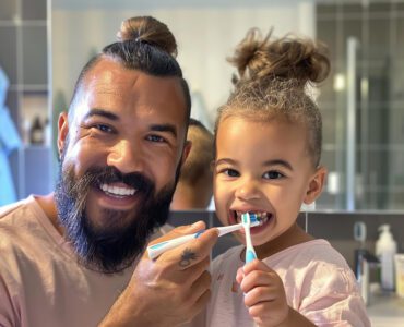 Pai escovando os dentes da filha com uma escova de dente infantil